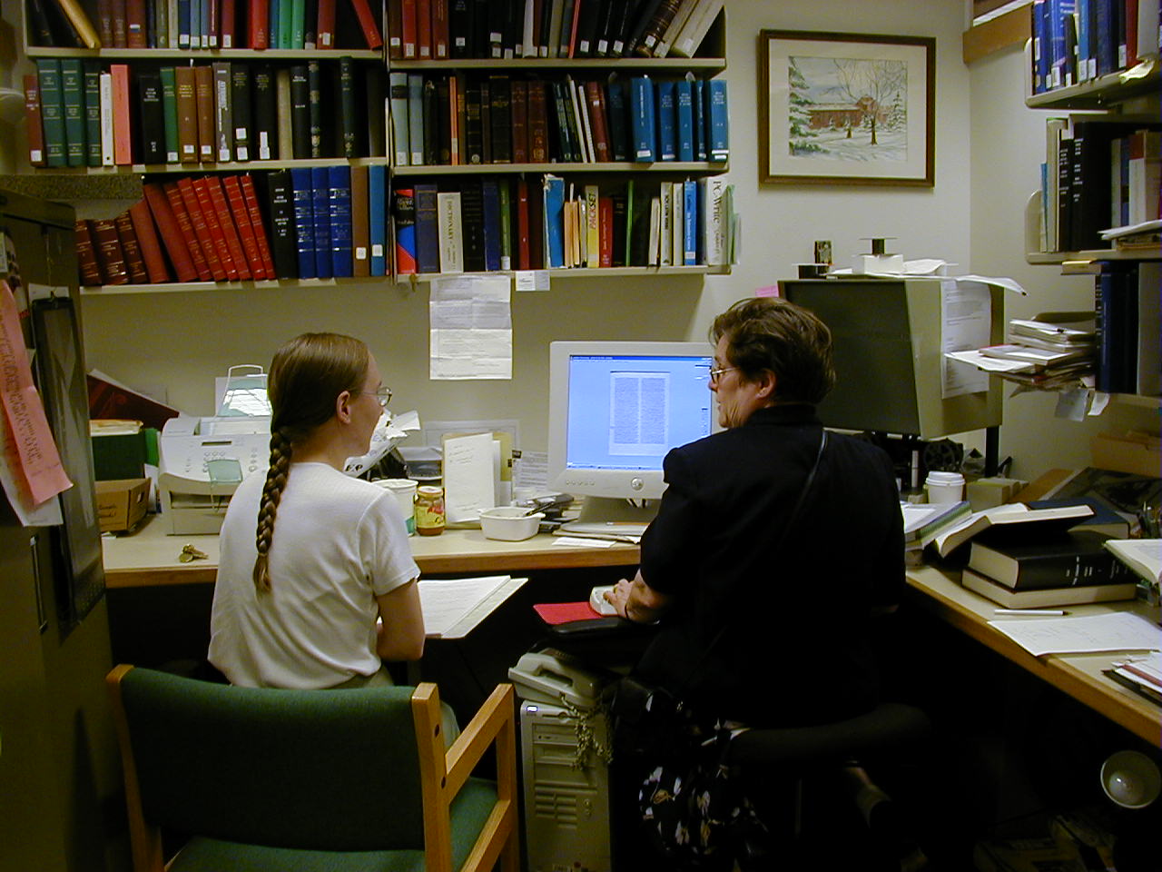 Photo of two editors collating manuscripts at a computer workstation