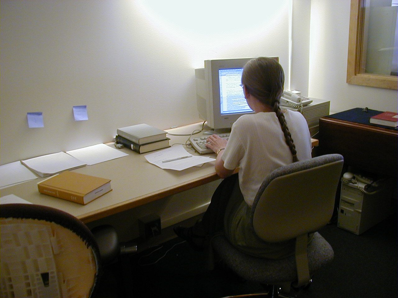 Photo of an editor working at a computer, writing notes for the final edition.